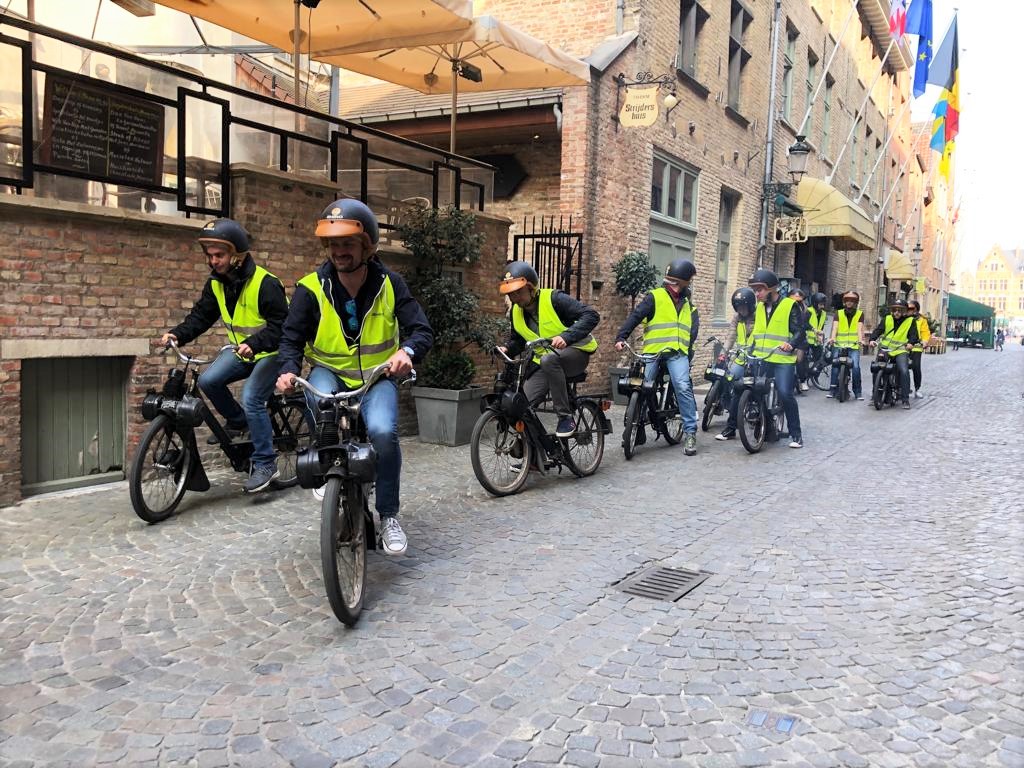 Deelnemers op Solex in een Brugse straat