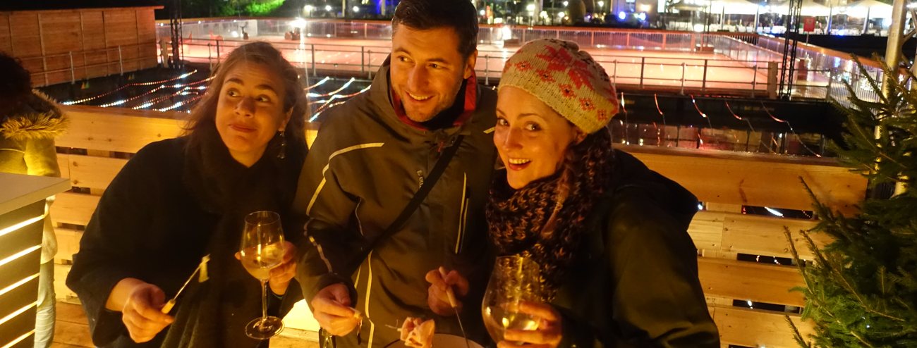 Deelnemers genieten van een kaasfondue met wijn in een sfeervolle winterse setting tijdens een Curling & Fondue-event